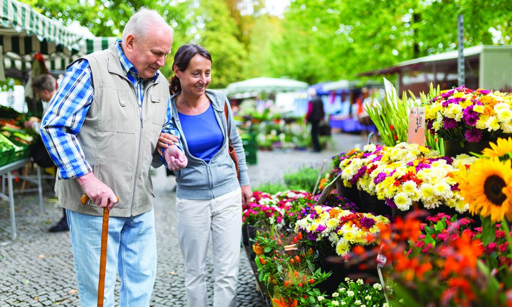 franchisee opportunity senior care provider and a client examine flowers at a market examining flowers